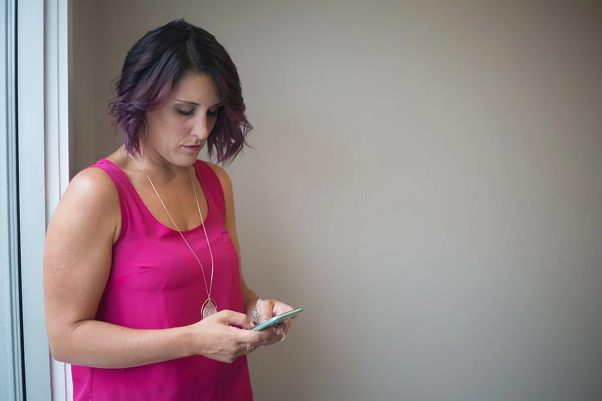 Woman looking at her smartphone beside a window