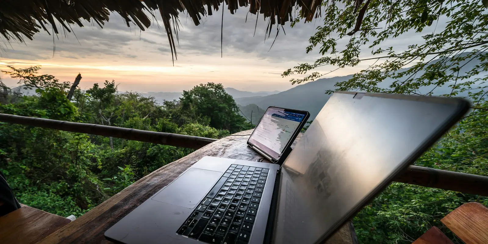 Portátil y teléfono sobre una mesa con vistas a la montaña