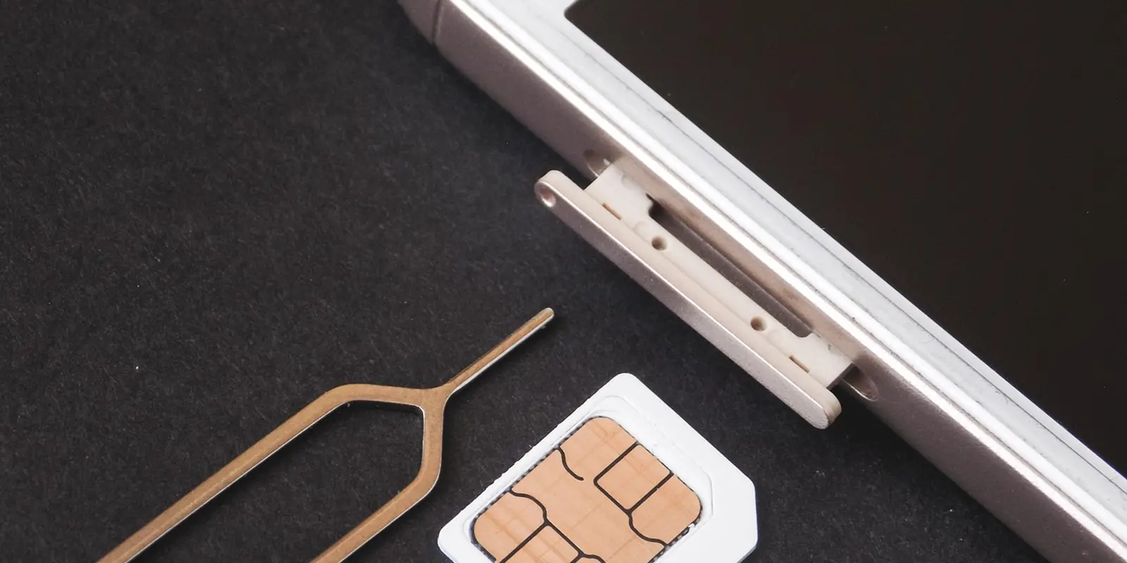 A physical SIM card can be removed and reused elsewhere — an eSIM profile is locked to one certified chip A physical SIM card resting beside a smartphone
