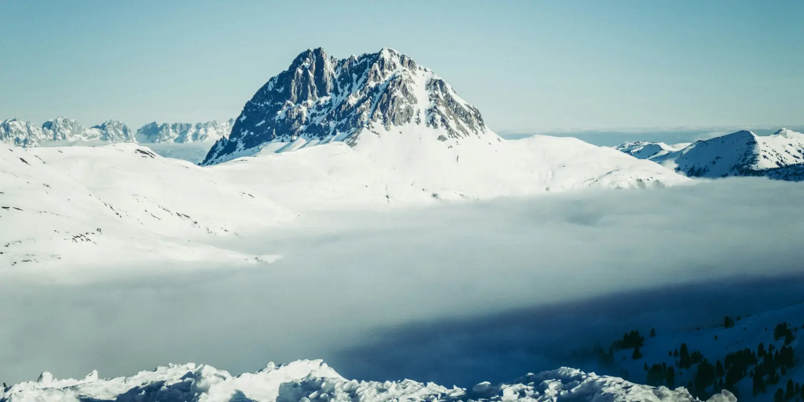Luftaufnahme schneebedeckter Alpengipfel in Österreich, dem Terrain rund um die Skigebiete, die die kostenlose eSIM abdeckt
