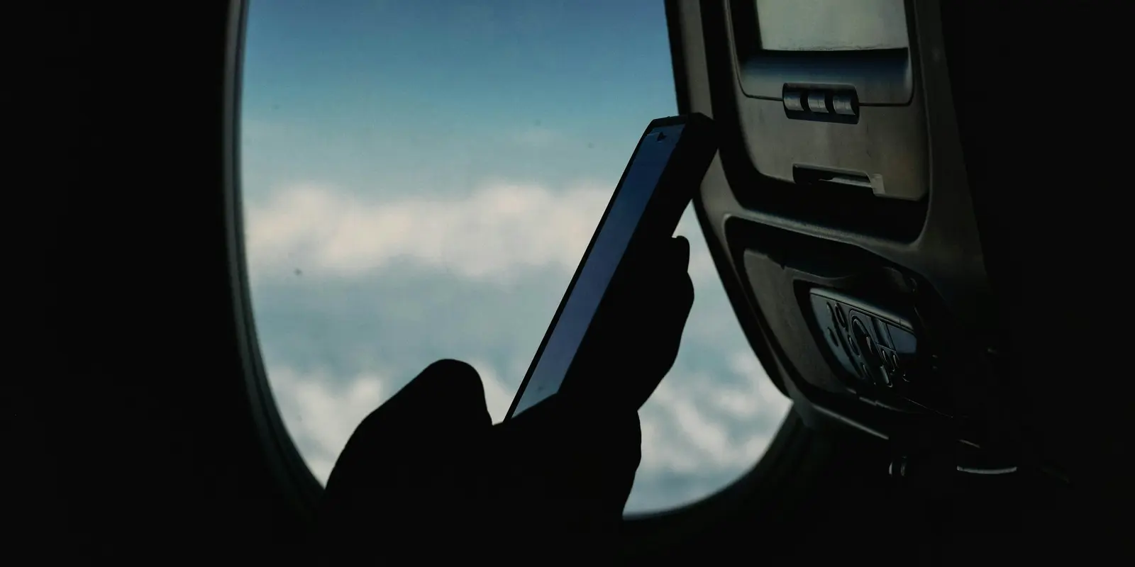 Checking eSIM trial terms before you travel saves surprises later A traveler checking their smartphone while seated on a plane