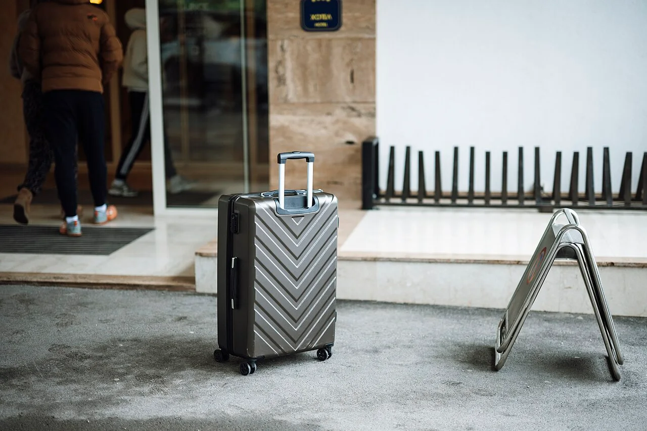 Travelers entering a hotel with a suitcase at the entrance