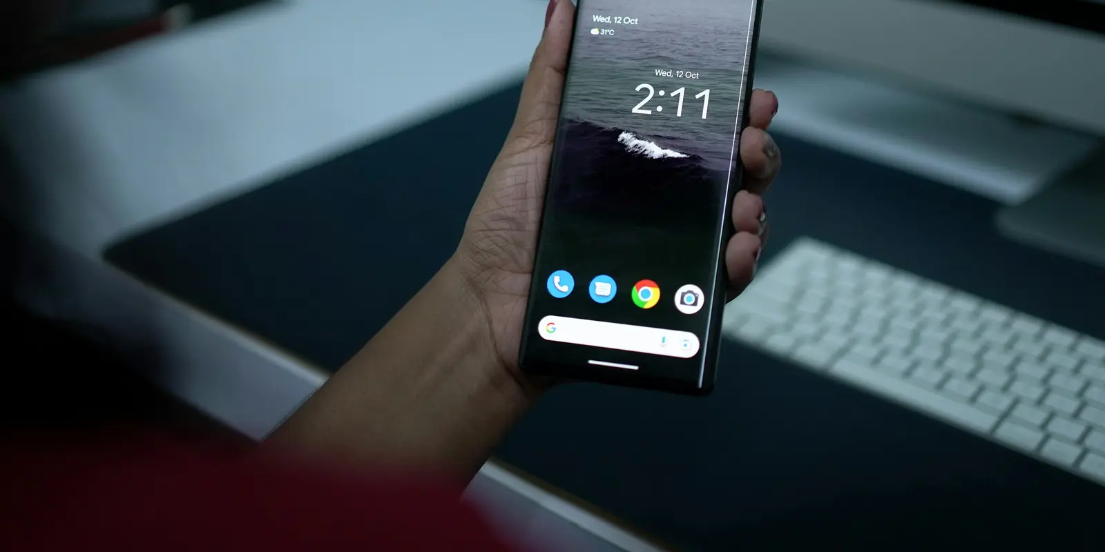 Una mano sosteniendo un Google Pixel con la pantalla de inicio visible