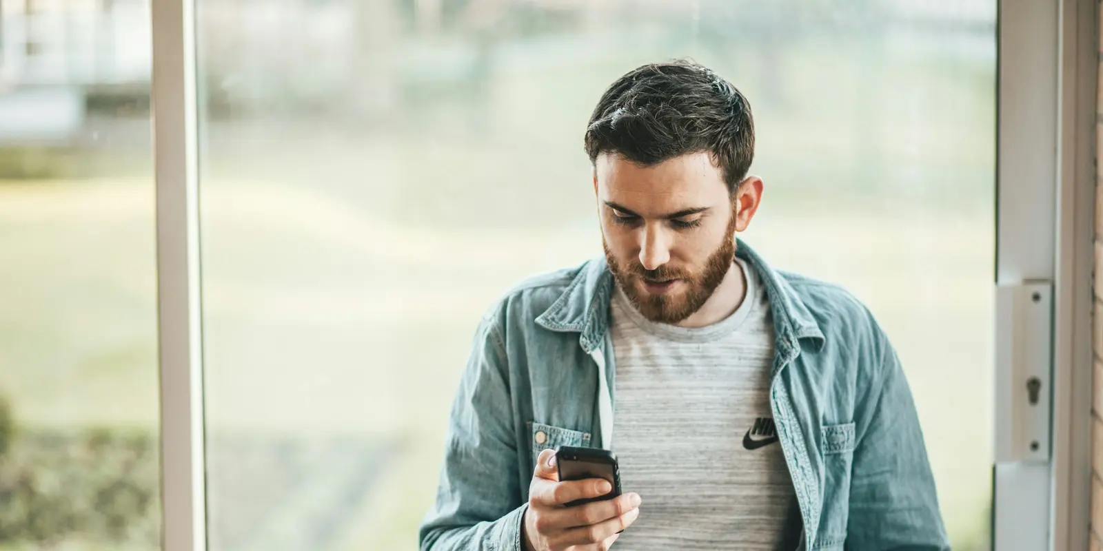 A person holding a smartphone up near a window, checking for signal